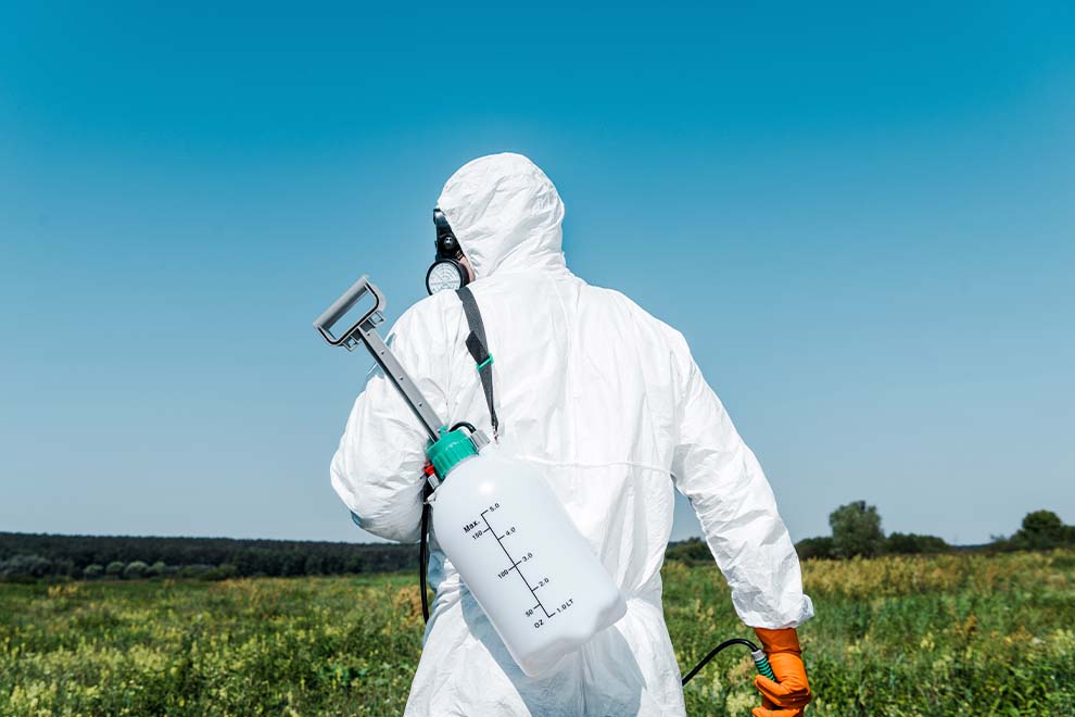 Trabalhador com traje de proteção em campo aberto